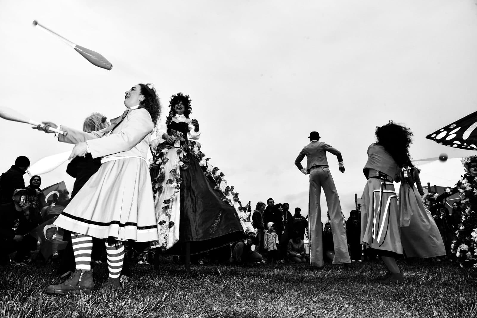 Jugglers and stilt walkers in costume performing for a crowd