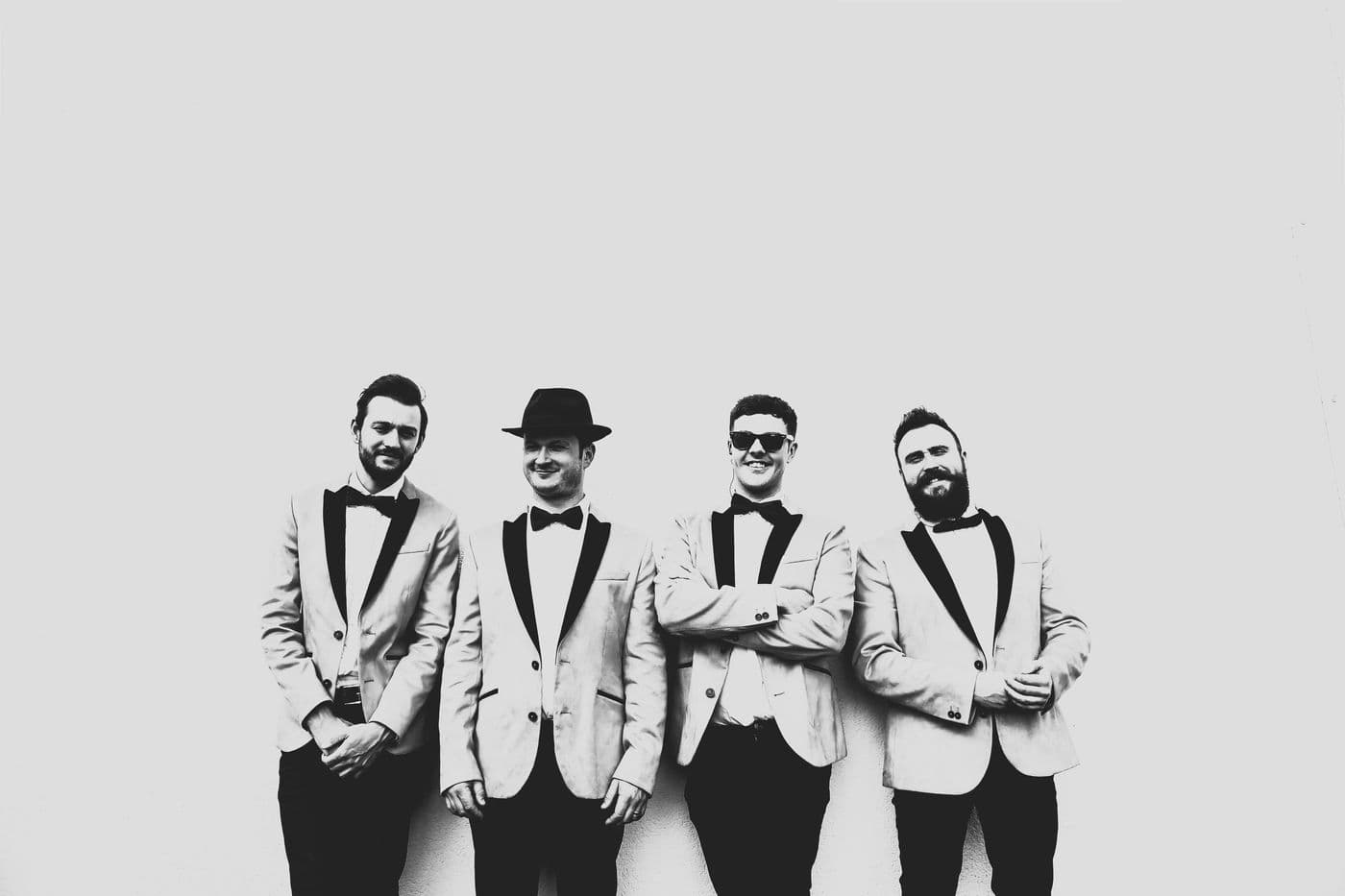 Four musicians in dinner jackets and bow ties, in black and white