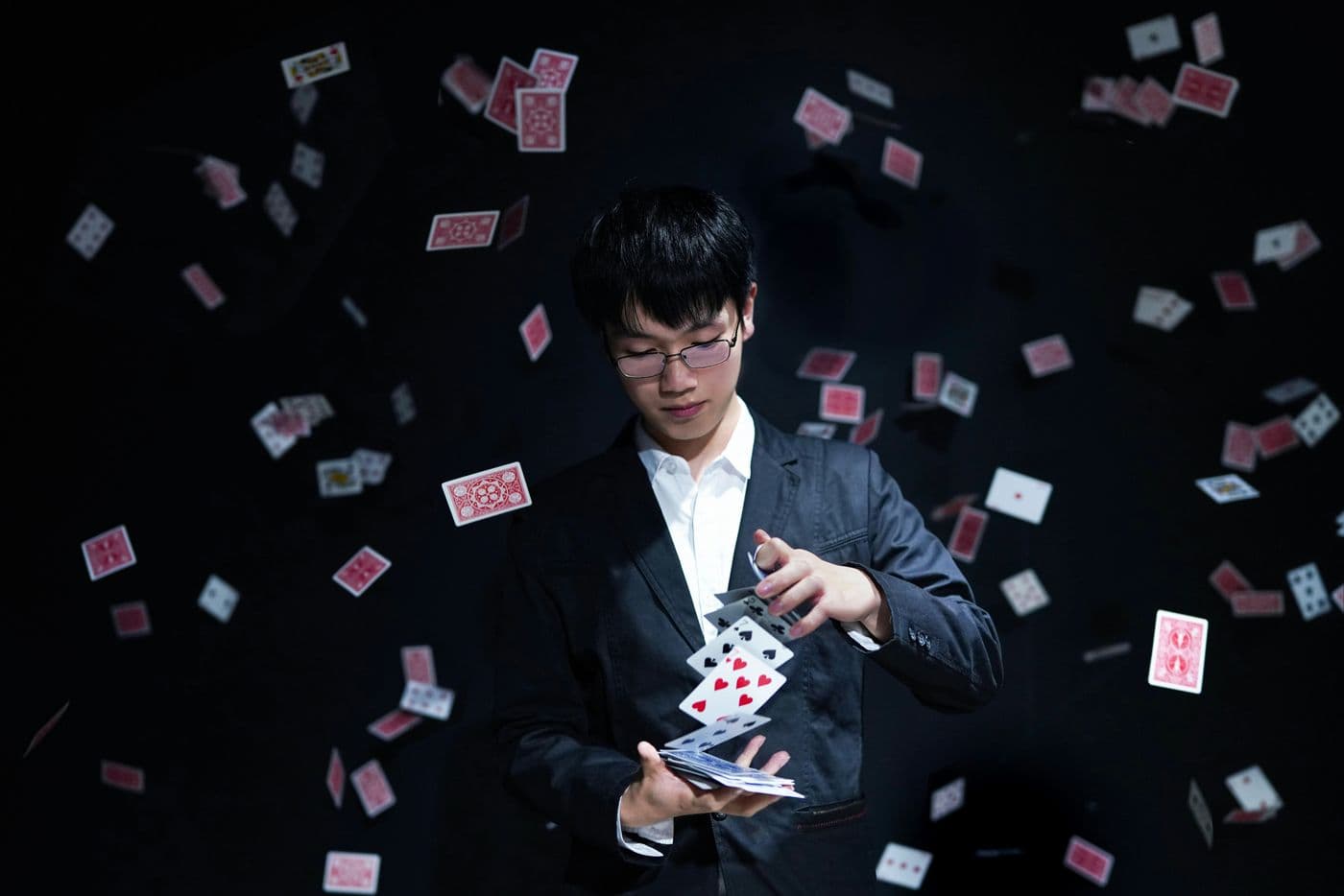 Magician sending playing cards flying around him