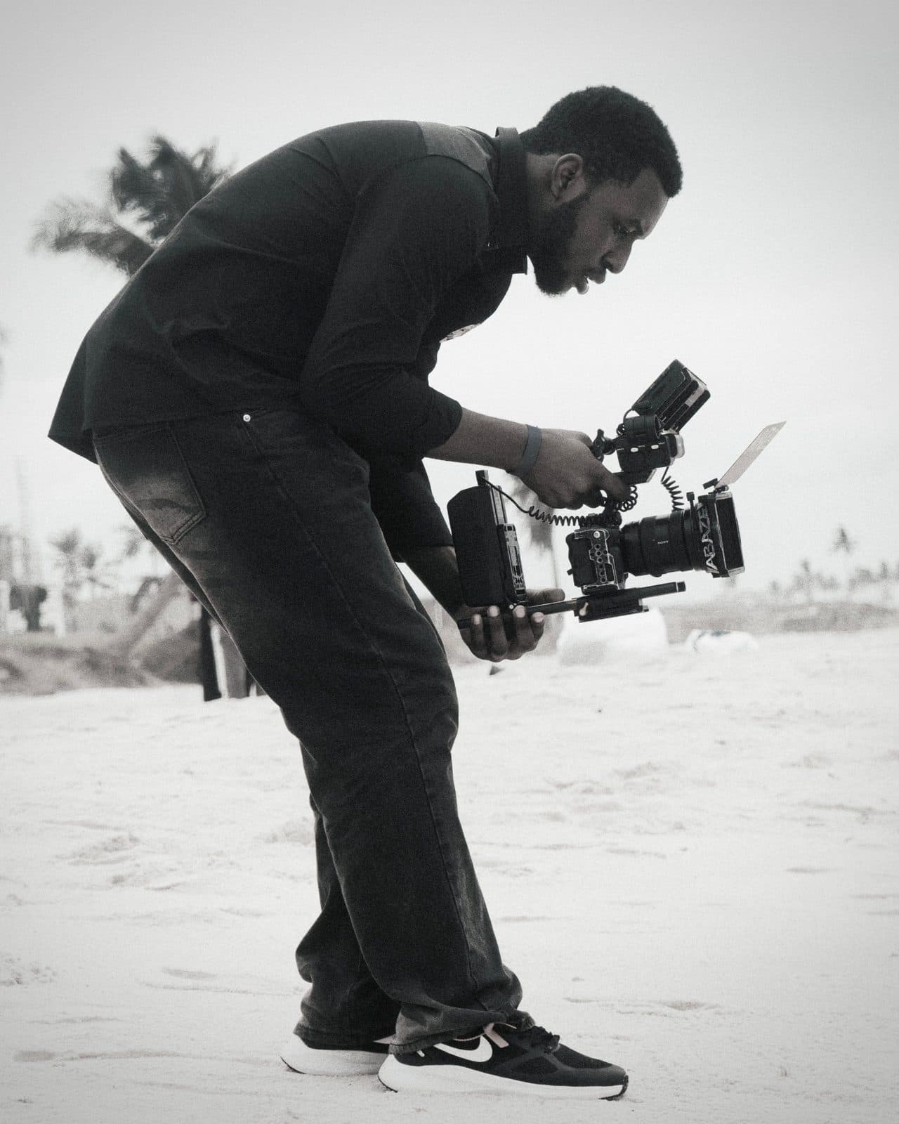 Videographer filming on a beach with a rig-mounted camera