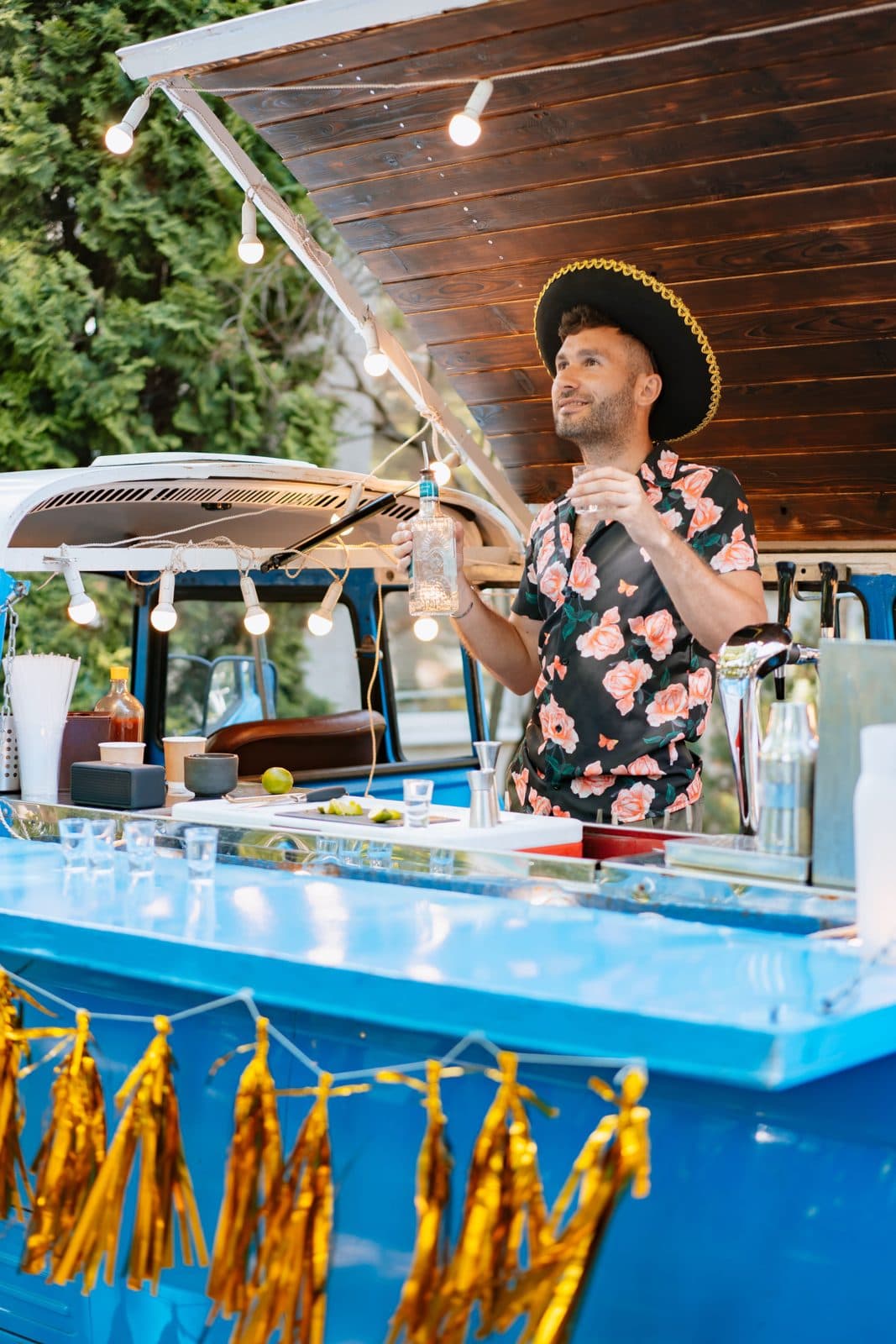 Smiling bartender behind the counter of a blue bar truck