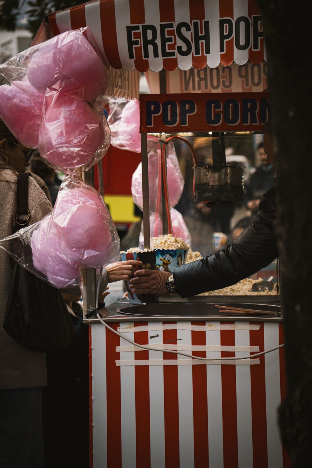 Barbe à papa roses devant un stand de pop-corn rayé