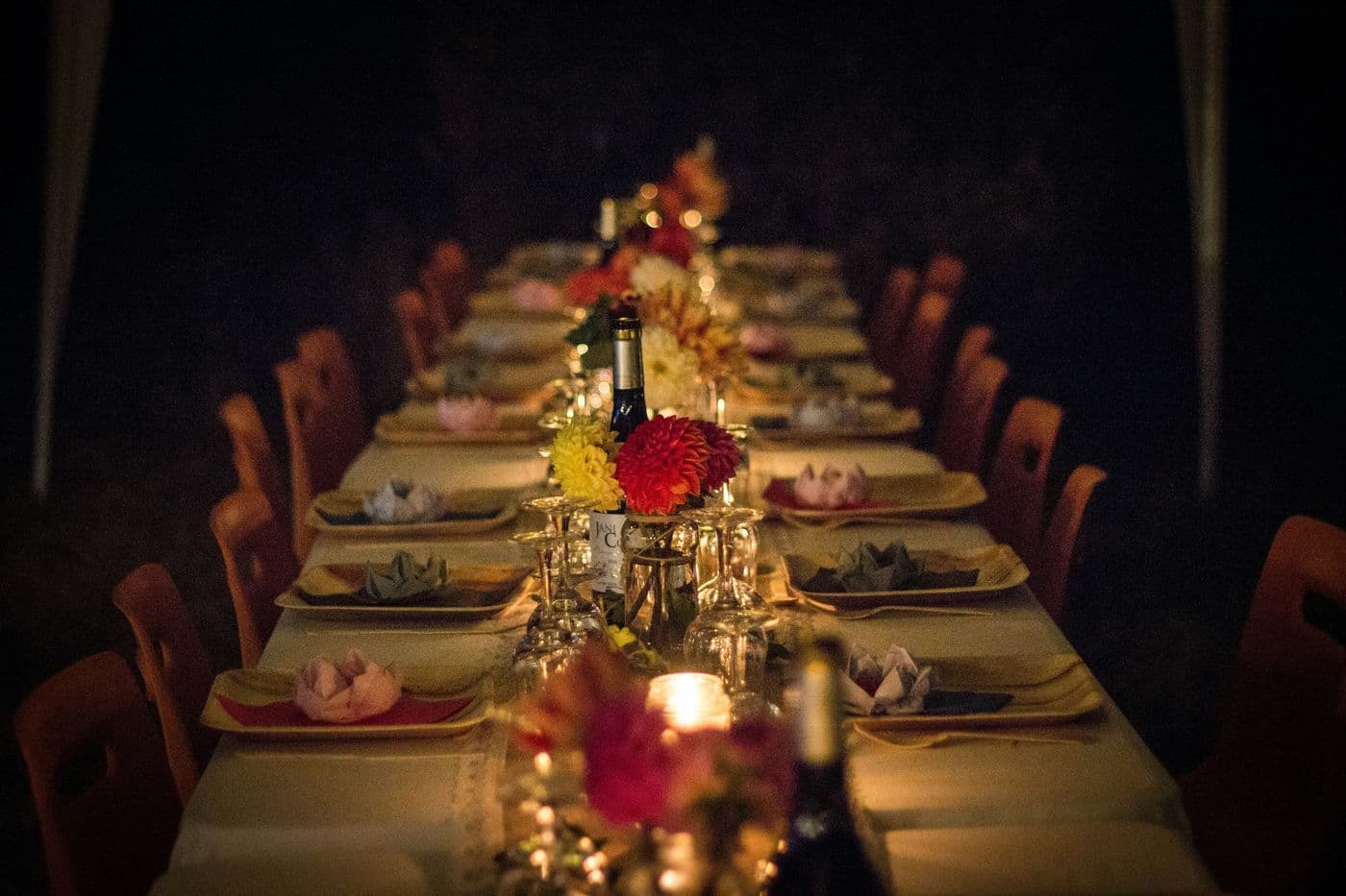 Long candlelit table set with flowers and wine for a celebration dinner