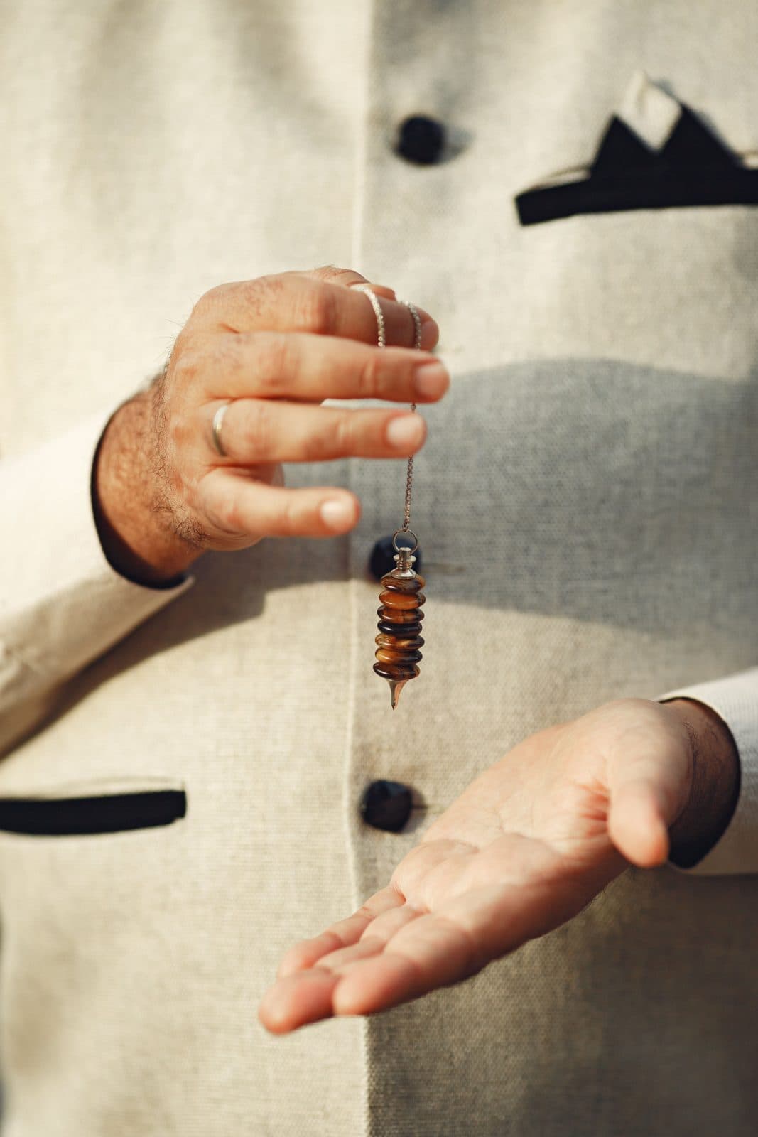 Hands holding a hypnotist's pendulum